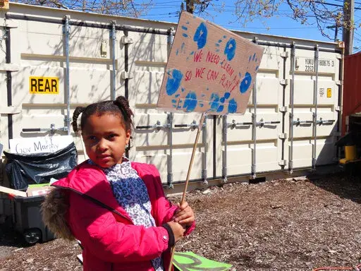 Eight-year-old Sapphire Tate holds a sign before a protest against a proposed backup power plant for a sewage treatment facility in Newark, N.J., on Wednesday, April 20, 2022. The Passaic Valley Sewerage Commission is pushing forward with the gas-fired power plant just months after New Jersey Gov. Phil Murphy ordered them to pause it to ensure that the project does not violate a soon-to-take-effect environmental justice law designed to protect communities that are already overburdened with sourc