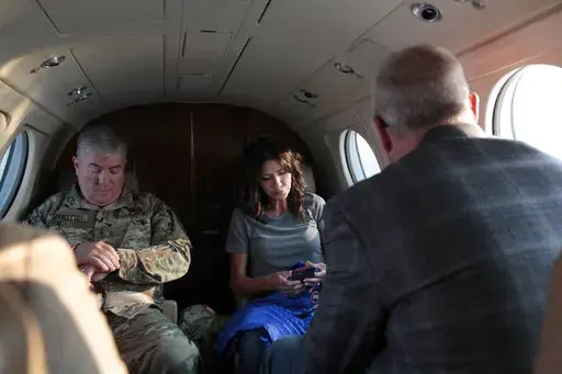 South Dakota Gov. Kristi Noem, center, checks her phone before taking off, Monday, July 26, 2021 in Pierre, S.D.  Noem is under investigation for using a state-owned airplane to fly to political events and bring family members with her on trips. But the decision on whether to prosecute the Republican governor likely hinges on how a county prosecutor interprets an untested law that was passed by voters in 2006. (AP Photo/Stephen Groves)