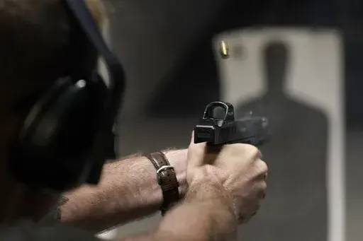 A man fires his pistol at an indoor shooting range during a qualification course to renew his Carry Concealed handgun permit at the Placer Sporting Club, July 1, 2022, in Roseville, Calif. A federal judge on Wednesday, Dec. 20, 2023, temporarily blocked a California law that would have banned carrying firearms in most public places, ruling that it violates the Second Amendment of the U.S. Constitution and deprives people of their ability to defend themselves and their loved ones. (AP Photo/Rich 