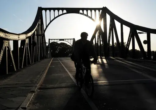 A cyclist passes over the Glienicke Bridge between Potsdam and Berlin, Germany, on May 6, 2009. They sometimes see those who are part of the swap as they pass each other on an airport tarmac or, as in the Cold War, the Glienicke Bridge connecting West Berlin to Potsdam. In decades of prisoner exchanges, those released have included spies, journalists, drug and arms dealers, and even a well-known athlete. (AP Photo/Sven Kaestner, File)