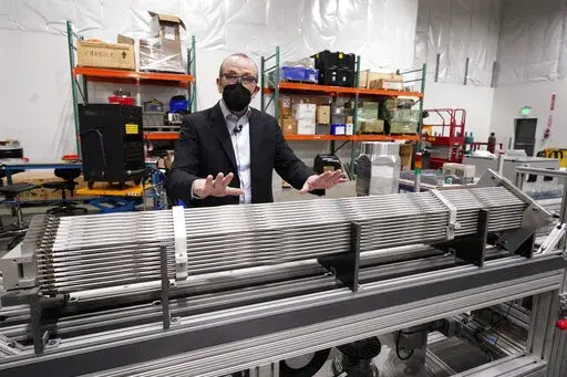 Chris Levesque, president and CEO of TerraPower, a company developing and building small nuclear reactors, displays a fuel assembly model, Thursday, Jan. 13, 2022, in Everett, Wash. The 5-foot model is about one-third actual length and would be vertical when in use, rather than horizontal. By cooling the reactor with liquid sodium, a metal that solidifies at well above room temperature, TerraPower says its relatively small, 345-megawatt plant will be safe and less expensive than conventional, wa