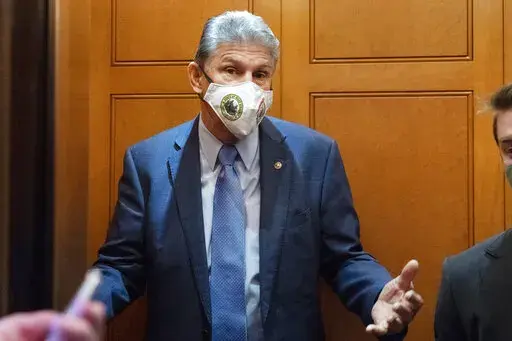 Sen. Joe Manchin, D-W.Va., a key vote on President Joe Biden's domestic spending agenda, gestures to reporters, Thursday, Dec. 2, 2021, while boarding an elevator on Capitol Hill in Washington. (AP Photo/Jacquelyn Martin)