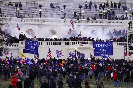 Violent insurrectionists loyal to President Donald Trump storm the Capitol, Jan. 6, 2021, in Washington. An Ohio man charged with stealing a coat rack from the U.S. Capitol doesn't deny that he joined the mob that stormed the building last year. But a lawyer for Capitol riot defendant Dustin Thompson vows to show that former President Donald Trump abused his power to authorize the attack on Jan. 6. (AP Photo/John Minchillo, File)