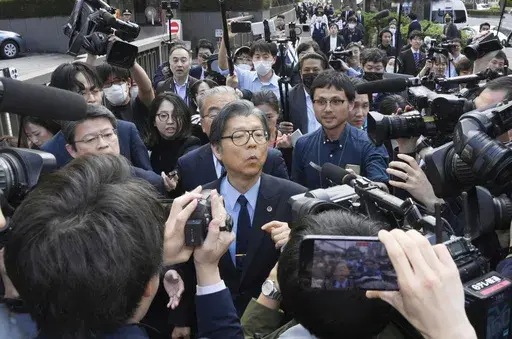 Nobuya Fukumoto, foreground center, a lawyer for the Unification Church, is surrounded by reporters after the church was ordered dissolved by the Tokyo District Court, in front of the court in Tokyo Tuesday, March 25, 2025. (Kyodo News via AP)