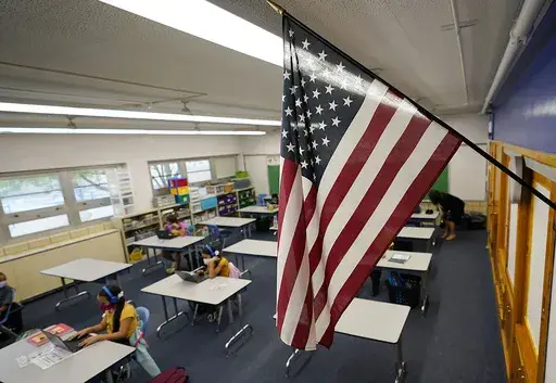 An American flag hangs in a classroom as students work on laptops in Newlon Elementary School, in Denver, Aug. 25, 2020. (AP Photo/David Zalubowski, File)