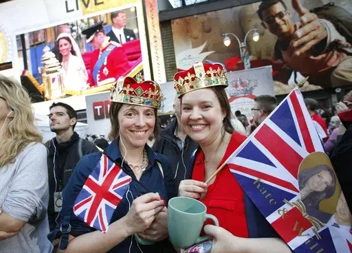 Molly Davis, left, and Amanda D'Aquila join a large crowd in New York's Times Square to watch the royal wedding, April 29, 2011. The pomp, the glamour, the conflicts, the characters — when it comes to the United Kingdom’s royal family, the Americans can’t seem to get enough. (AP Photo/Mark Lennihan, File)