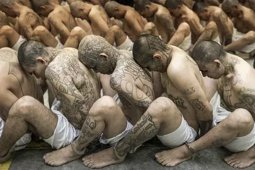 In this photo provided by El Salvador's presidential press office, inmates identified by authorities as gang members are seated on the prison floor of the Terrorism Confinement Center in Tecoluca, El Salvador, Wednesday, March 15, 2023. (El Salvador presidential press office via AP)