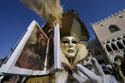 A man wears a mask and holds the replica a the book 'The Million" a report of Marco Polo's travels in Asia, during the Carnival in Venice, Italy, Sunday Jan. 28, 2024. Venice is marking the 700th anniversary of the death of Marco Polo with a yearlong series of commemorations, starting with the opening of Carnival season honoring one of the lagoon city's most illustrious native sons. (AP Photo/Luca Bruno)