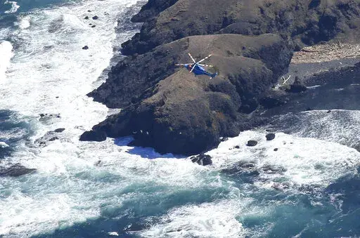 A helicopter hovers over the tip of Shiretoko Peninsula in northern Japan of Hokkaido to conduct a search operation Monday, April 25, 2022. Rescuers continue the search operation for the missing since a tour boat carrying 26 people apparently sank off far northeastern Japan. (Kyodo News via AP)