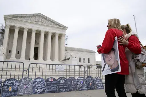 Jen Trejo holds a photo of her son Christopher as she is comforted outside the Supreme Court Monday, Dec. 4, 2023, in Washington. Her son was 32 when he died and she said about Purdue Pharma and the Sackler family, "You can't just kill my child and just pay a fine." The Supreme Court is wrestling with a nationwide settlement with OxyContin maker Purdue Pharma that would shield members of the Sackler family who own the company from civil lawsuits over the toll of opioids. (AP Photo/Stephanie Scar