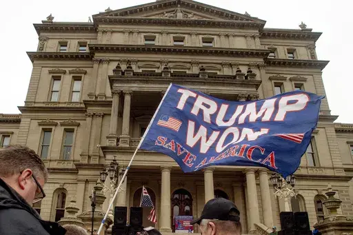 A protester waves a Trump flag during rally organized by a group called Election Integrity Fund and Force at the Michigan State Capitol, Tuesday, Oct. 12, 2021, in Lansing, Mich. Michigan Attorney General Dana Nessel has charged 16 Republicans Tuesday, July 18, 2023, with multiple felonies after they are alleged to have submitted false certificates stating they were the state’s presidential electors despite Joe Biden’s 154,000-vote victory in 2020. The group includes Republican National Comm