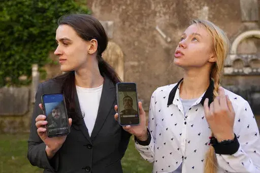 Kateryna Prokopenko, wife of Denys Prokopenko, commander of the Azov regiment, right, and Yulia Fedosiuk, wife of Arseny Fedosiuk, another member of Azov regiment get emotional as they show photos of their husbands on their phones during an interview with the Associated Press in Rome, Friday, April 29, 2022. Two Ukrainian women whose husbands are defending a besieged steel plant in the southern city of Mariupol are calling for any evacuation of civilians to also include soldiers. They say the tr