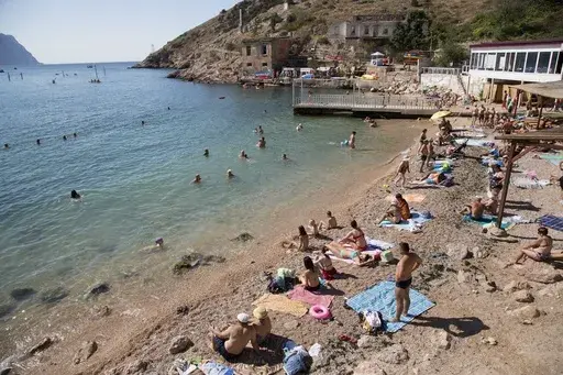People gather at the beach area of the Black Sea, in Balaklava's bay, a part of Sevastopol on the Crimean Peninsula on Sunday, Aug. 9, 2015. The Crimean Peninsula's balmy beaches have been vacation spots for Russian czars and has hosted history-shaking meetings of world leaders. And it has been the site of ethnic persecutions, forced deportations and political repression. Now, as Russia’s war in Ukraine enters its 18th month, the Black Sea peninsula is again both a playground and a battlegroun