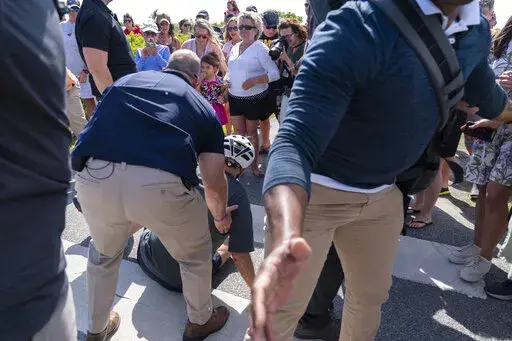 President Joe Biden is helped by U.S. Secret Service agents after he fell trying to get off his bike to greet a crowd on a trail at Gordons Pond in Rehoboth Beach, Del., Saturday, June 18, 2022.  On Friday, June 24, The Associated Press reported on stories circulating online incorrectly claiming the Atlantic published an article with the headline, “The Heroism of Biden’s Bike Fall” after Biden fell on Saturday as he tried to dismount his bicycle. (AP Photo/Manuel Balce Ceneta, File)