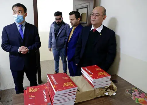 Chinese lecturer, Zhiwei Hu, left, teachers and officials of the Chinese Language Department stand in front of Chinese language books intended for students in Salahaddin University in Irbil, Iraq, Wednesday, Jan. 19, 2021. The Chinese language school in northern Iraq is attracting students who hope to land jobs with a growing number of Chinese companies in the oil, infrastructure, construction, and telecommunications sectors in the region. (AP Photo/Khalid Mohammed)