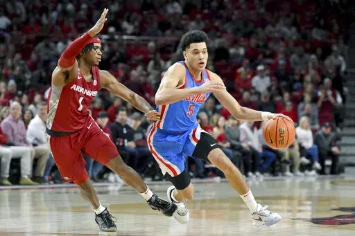 Mississippi guard James White (5) drives past Arkansas guard Ricky Council IV (1) during the first half of an NCAA college basketball game Saturday, Jan. 21, 2023, in Fayetteville, Ark. (AP Photo/Michael Woods)