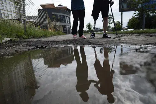 Roman Yarmolenko, a Ukrainian soldier from the 93rd brigade, learns to walk on a prosthetic leg. He crosses rough, muddy terrain outside the Unbroken rehabilitation center in Lviv, Ukraine, Wednesday, July 26, 2023. Ukraine is facing the prospect of a future with upwards of 20,000 amputees, many of them soldiers who are also suffering psychological trauma from their time at the front. (AP Photo/Evgeniy Maloletka)