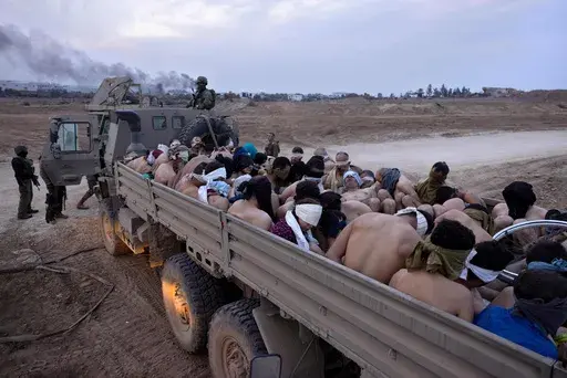 Israeli soldiers stand by a truck packed with bound and blindfolded Palestinian detainees, in Gaza, Dec. 8, 2023. (AP Photo/Moti Milrod, Haaretz, File)