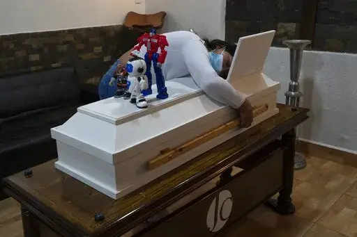 Julieres Acevedo hugs the coffin holding her 4-year-old son Joshue the day after he died during his wake in Caracas, Venezuela, Wednesday, Oct 27, 2021. Joshue, who had leukemia, died while waiting for a bone marrow transplant. (AP Photo/Ariana Cubillos)