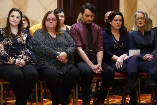 Families of the victims of the Newtown shooting and attorneys listen during a news conference in Trumbull, Conn., Tuesday, Feb. 15, 2022. The families of nine victims of the Sandy Hook Elementary School shooting have agreed to a $73 million settlement of a lawsuit against the maker of the rifle used to kill 20 first graders and six educators in 2012, their attorney said Tuesday. (AP Photo/Seth Wenig)