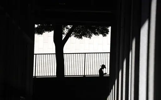 A person is silhouetted against a wall as they look down at their cell phone outside the Clara Shortridge Foltz Criminal Justice Center on July 29, 2021, in Los Angeles. With abortion now or soon to be illegal in over a dozen states and severely restricted in many more, Big Tech companies that vacuum up personal details of their users are facing new calls to limit that tracking and surveillance. One fear is that law enforcement or vigilantes could use those data troves against people seeking way