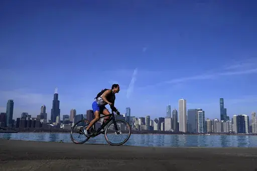 A cyclist travels around Lake Michigan near the Adler Planetarium Monday, Feb. 26, 2024, in Chicago. Federal meteorologists on Friday, March 8, have made it official: It's the warmest U.S. winter on record by far. (AP Photo/Charles Rex Arbogast, File)