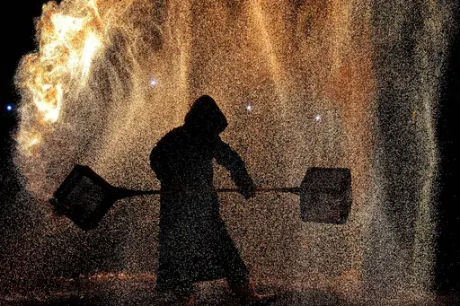 An artist performs a fire kettle show during the Mid-Autumn Festival at a night market in Beijing, Tuesday, Sept. 17, 2024. (AP Photo/Andy Wong)