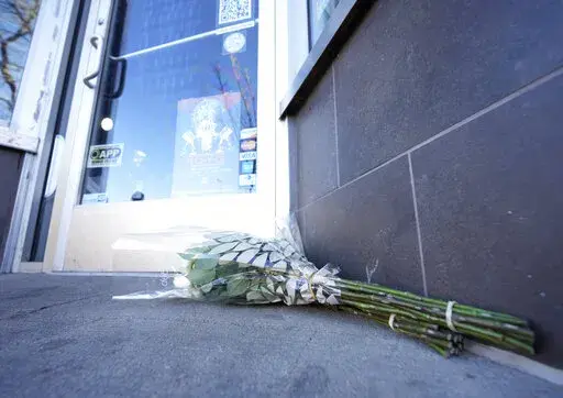 Bouquets of flowers are placed outside the door of a tattoo parlor along South Broadway Tuesday, Dec. 28, 2021 in Denver, one of the scenes of a shooting spree that left five people dead—including the suspected shooter Monday evening—and left a few more people wounded. The spree spread from the core of Denver to the western suburb of Lakewood where the suspect was shot and killed by police near a busy intersection in a bustling shopping district. (AP Photo/David Zalubowski)