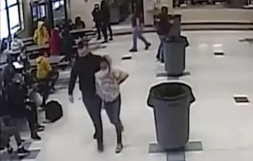 In this frame grab from surveillance video provided by the Kenosha Unified School District, an off-duty police officer escorts a 12-year-old student out of a school cafeteria following a lunchtime fight, in Kenosha, Wis., on March 4, 2022. Earlier in the video, the officer, who was working as a security guard, is shown intervening in the fight and putting his knee on the girl’s neck to restrain her. (Kenosha Unified School District via AP)