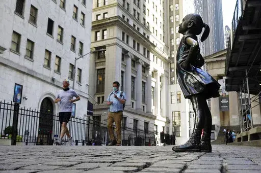 In this June 16, 2021, photo, the "Fearless Girl" statue faces the New York Stock Exchange. The 4-foot bronze "Fearless Girl" statue that was installed opposite New York City's Charging Bull in 2017 will remain in its current spot opposite the New York Stock Exchange at least until early 2023 while city officials wrestle with a permanent disposition for the popular symbol of female empowerment, a city board decided Monday, April 11, 2022. (AP Photo/Richard Drew, File)