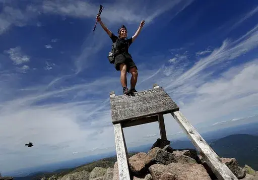 Jesse Metzler, of Newton, Ma., who goes by the trail name "Sputnik," celebrates on the top of a sign marking the northern terminus of the Appalachian Trail at the summit of Mt. Katahdin, July 19, 2015, in Baxter State Park, Maine. A proposal before the Maine Legislature would ask voters to approve $30 million in public money for the design, development and maintenance of both motorized and non-motorized trails. (Derek Davis/Portland Press Herald via AP, File)