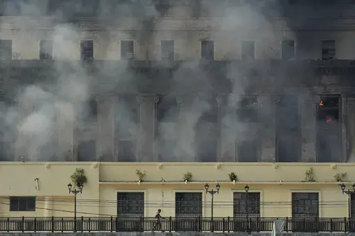 A man passes by the still smoldering Manila Central Post Office after it caught fire early Monday, May 22, 2023 in Manila, Philippines. On Friday, July 7, The Associated Press reported on stories circulating online incorrectly claiming a video shows a major library in France burning during riots sparked by the police killing of a 17-year-old. (AP Photo/Aaron Favila, File)