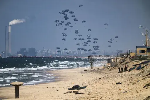 An aircraft airdrops humanitarian aid over the northern Gaza Strip, as seen from central Gaza, Monday, March 25, 2024. (AP Photo/Fatima Shbair)