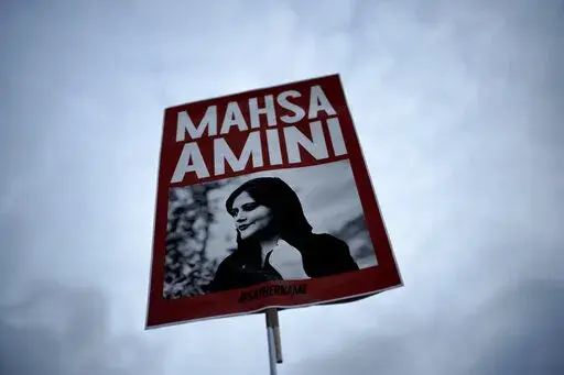 A woman holds a placard with a picture of Iranian woman Mahsa Amini during a protest against her death, in Berlin, Germany, Wednesday, Sept. 28, 2022.  Iranian celebrities have been startlingly public in their support for the massive anti-government protests shaking their country. And the ruling establishment is lashing back. Celebrities have found themselves targeted for arrest, have had passports confiscated and faced other harassment. (AP Photo/Markus Schreiber, File)