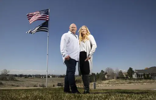 Jennifer and Tim Kohl poses for a photo in their front yard with the American flag and a thin blue line flag in Star, Idaho, on April 14, 2023. The couple recently moved to Idaho from the Los Angeles area. Americans are segregating by their politics at a rapid clip, helping fuel the greatest divide between the states in modern history. (AP Photo/Kyle Green)