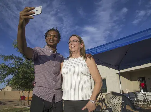 Jamal Hinton, left, and Wanda Dench take a selfie together after meeting at Dench's home for Thanksgiving dinner on Nov. 24, 2016, in Mesa, Ariz. Dench, an Arizona woman who opened her Thanksgiving table to Hinton, a stranger she accidentally texted, will be opening up her home again this year to two new strangers. Dench is teaming up with Airbnb to expand the festivities, and the company will be making a donation to the relief organization Feeding America. (Tom Tingle/The Arizona Republic via A