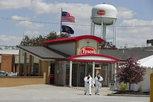 In this May 7, 2020 file photo, workers leave the Tyson Foods pork processing plant in Logansport, Ind.  For the first time in two years for many people, the American workplace is transforming into something that resembles pre-pandemic days. The U.S. has since seen COVID-19 infections and hospitalizations plummet. Cases have plunged from 455,000 a day two weeks ago to 150,000 on Monday, Feb. 14, 2022. (AP Photo/Michael Conroy, File)