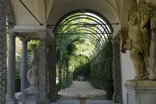 A man sits on a bench near the pavilion in the newly restored garden of the Rubens House in Antwerp, Belgium, Wednesday, Aug. 28, 2024. (AP Photo/Virginia Mayo)
