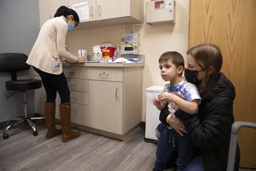 Ilana Diener holds her son, Hudson, 3, during an appointment for a Moderna COVID-19 vaccine trial in Commack, N.Y. on Nov. 30, 2021. On Thursday, April 28, 2022, Moderna asked U.S. regulators to authorize low doses of its COVID-19 vaccine for children younger than 6, a long-awaited move toward potentially opening shots for millions of tots by summer. (AP Photo/Emma H. Tobin, File)