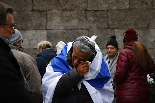 Zvika Karavany, 72, a Yemeni-born Israeli, wipes his tears in front of the Death Wall in the former Nazi German concentration and extermination camp Auschwitz during ceremonies marking the 78th anniversary of the liberation of the camp in Oswiecim, Poland, Friday, Jan. 27, 2023. (AP Photo/Michal Dyjuk)